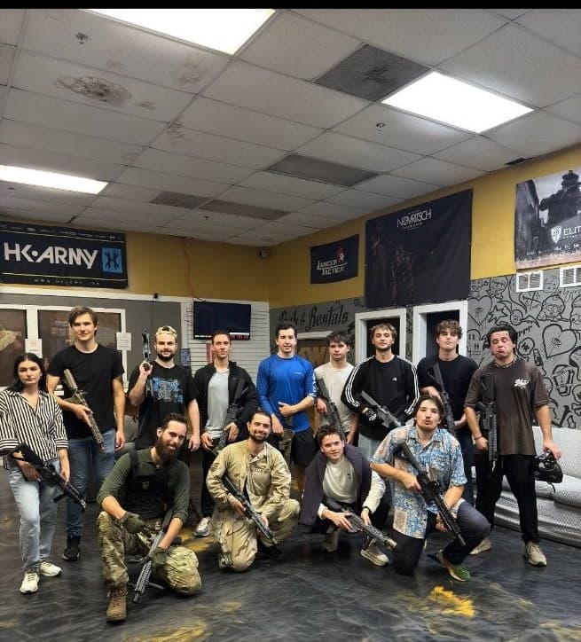 Tampa Bay 20s members holding airsoft rifles on an indoor field