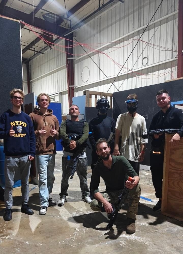 Group in masks and gear inside a warehouse airsoft arena