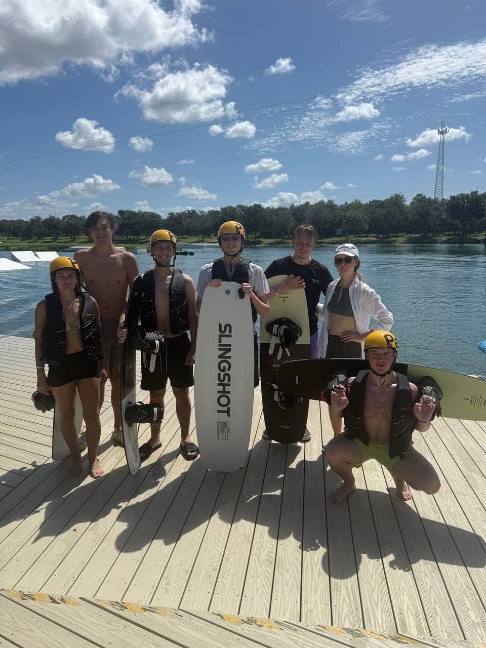 Friends holding wakeboards on the dock of a cable park